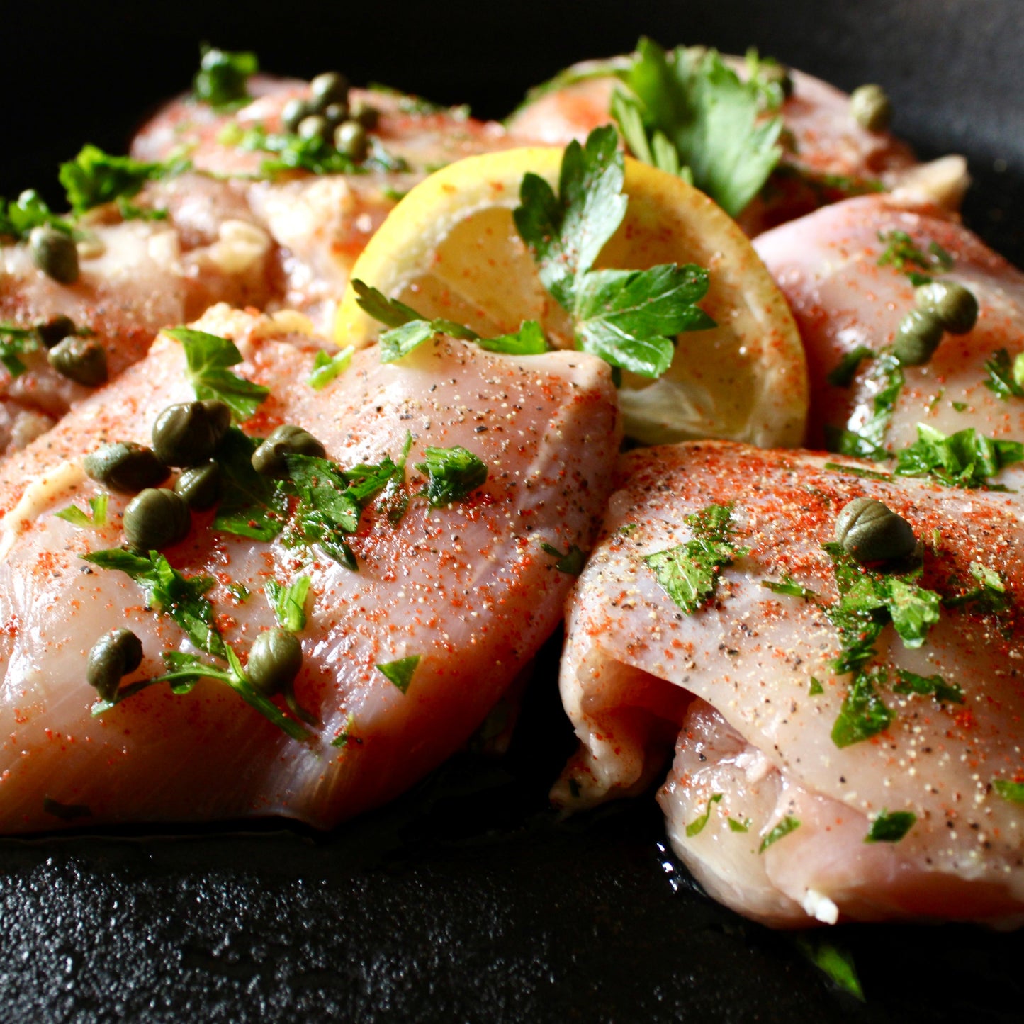 6 seasoned boneless chicken thigh pieces with herbs and lemon in a cast iron skillet