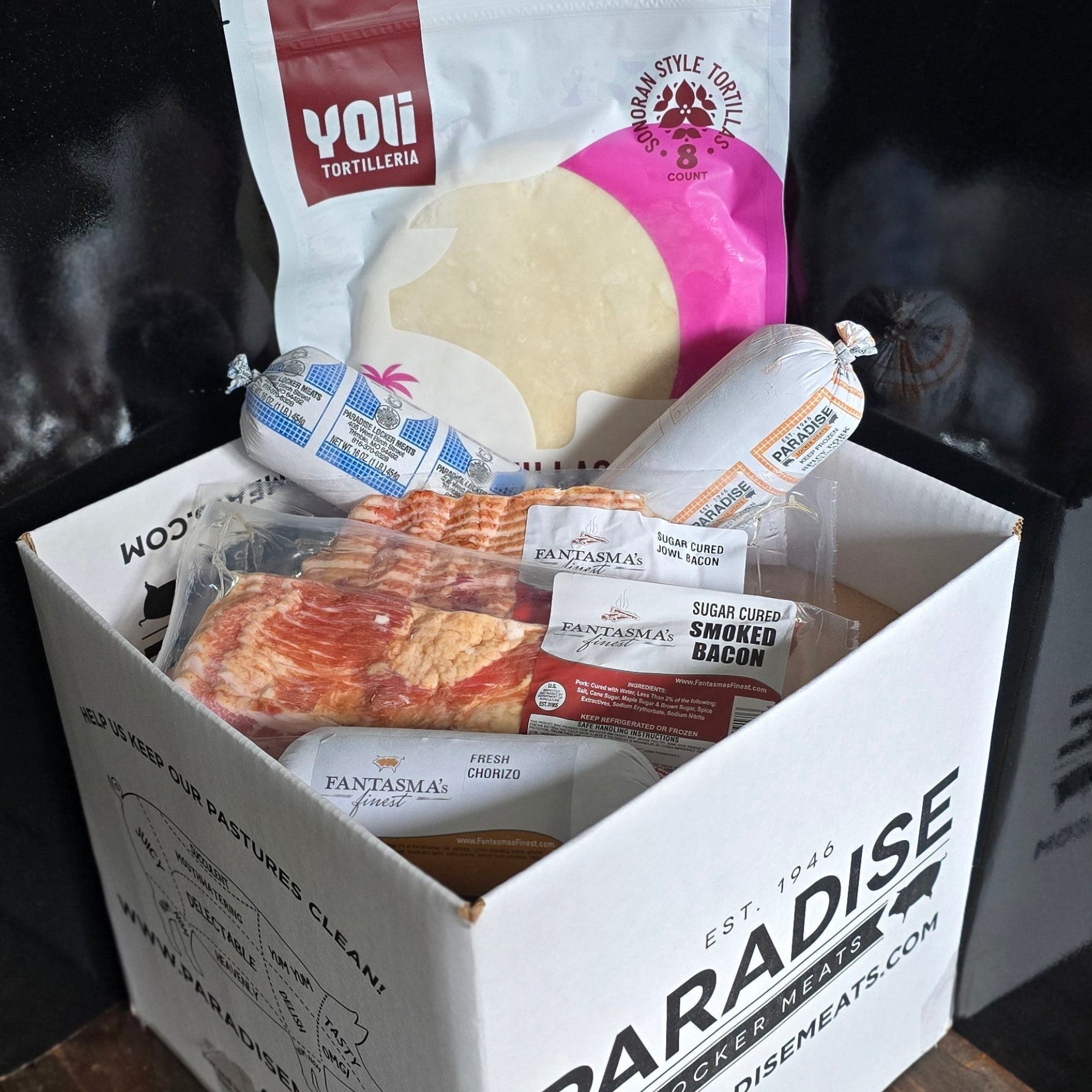 Box labeled 'Paradise' with various items on a wooden surface