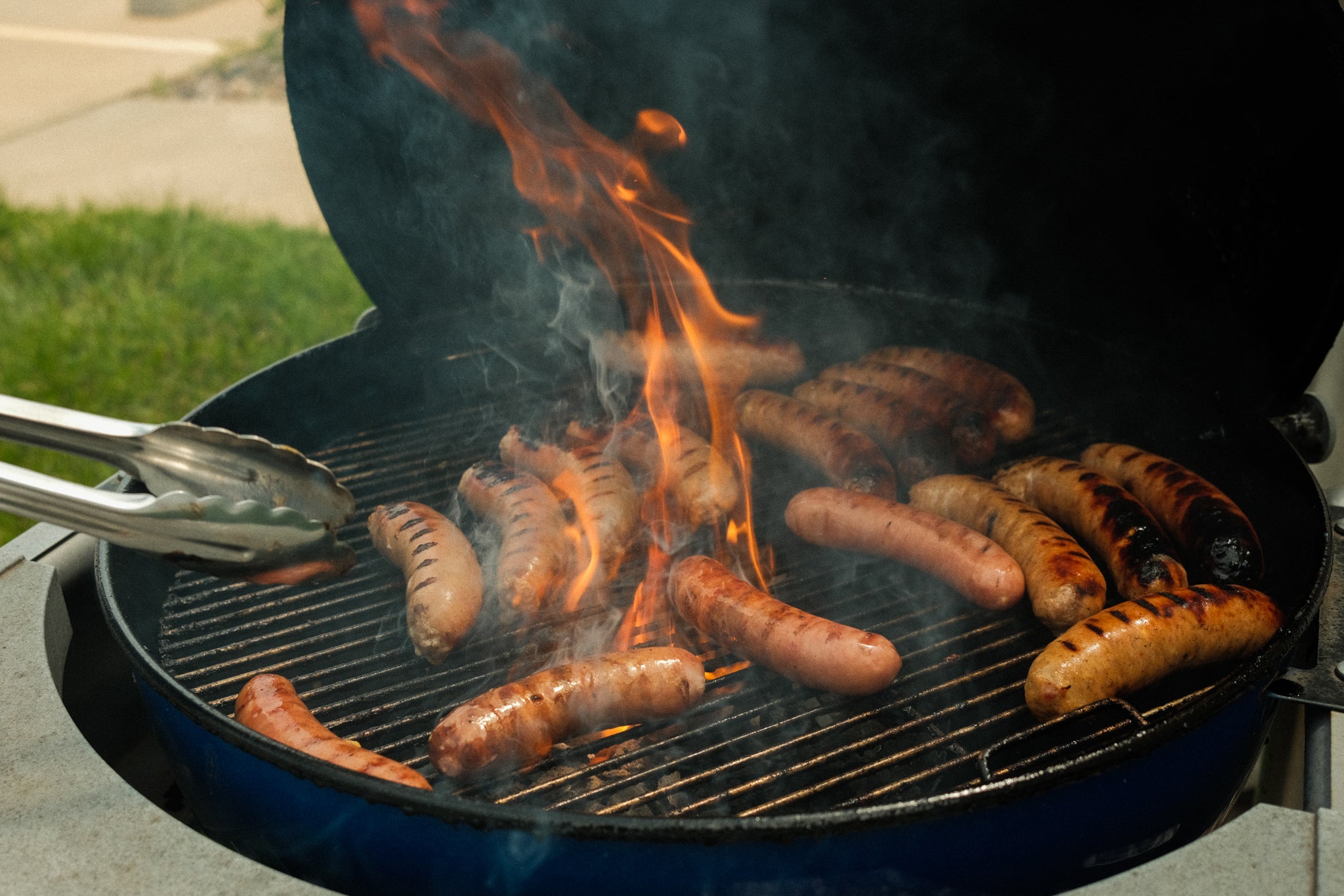 Brats being fire roasted on a grill