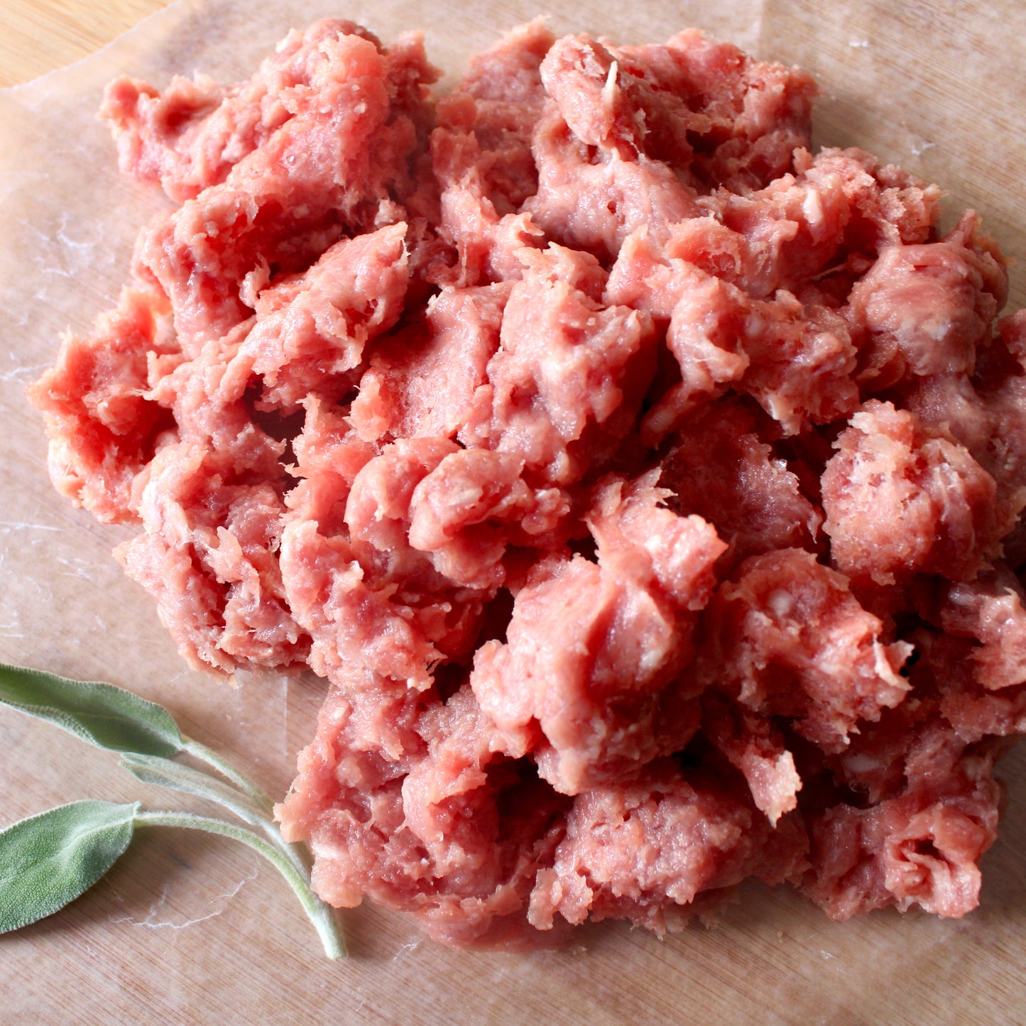 Ground Chicken on cutboard background with sage leaves