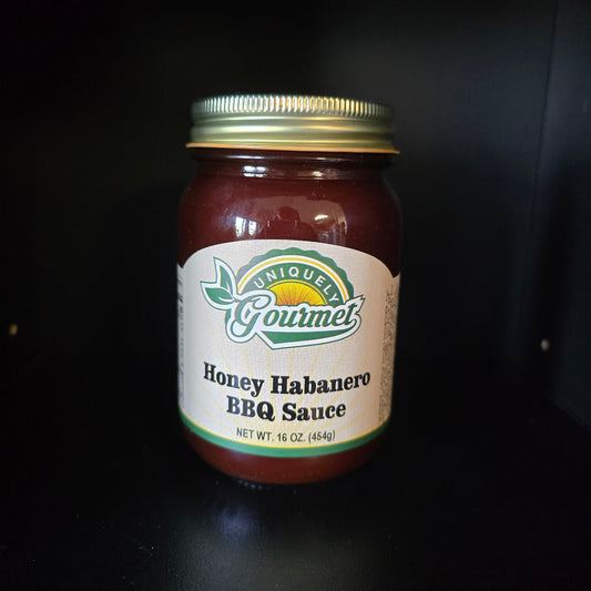 A glass jar of Quiksort Gourmet Honey Habanero BBQ Sauce with a gold metal lid and a white label, set against a dark black background.