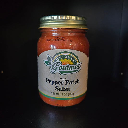 A jar of Unique Gourmet Mild Pepper Patch Salsa on a dark background.