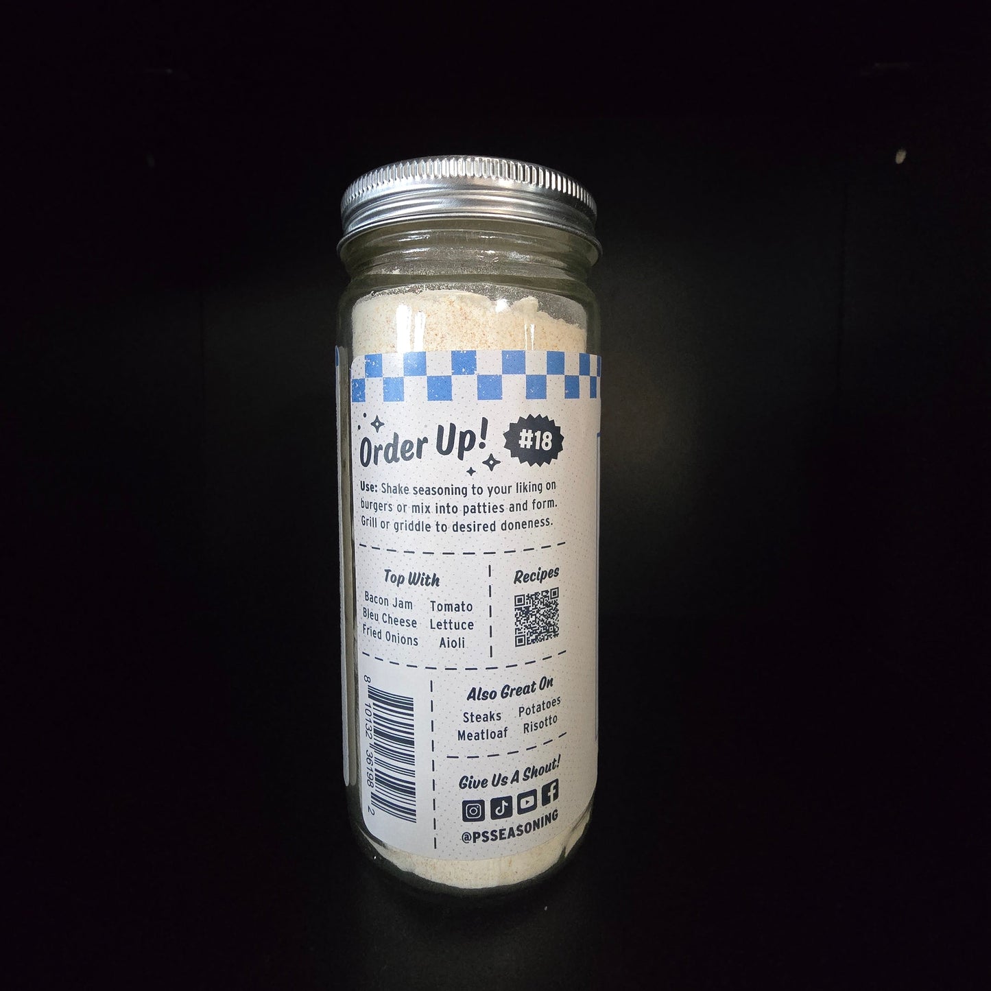 A clear glass jar sealed with a silver metal lid, and standing upright against a black background. The label reads 'Order Up!' with a blue-and-white check pattern and small text below.