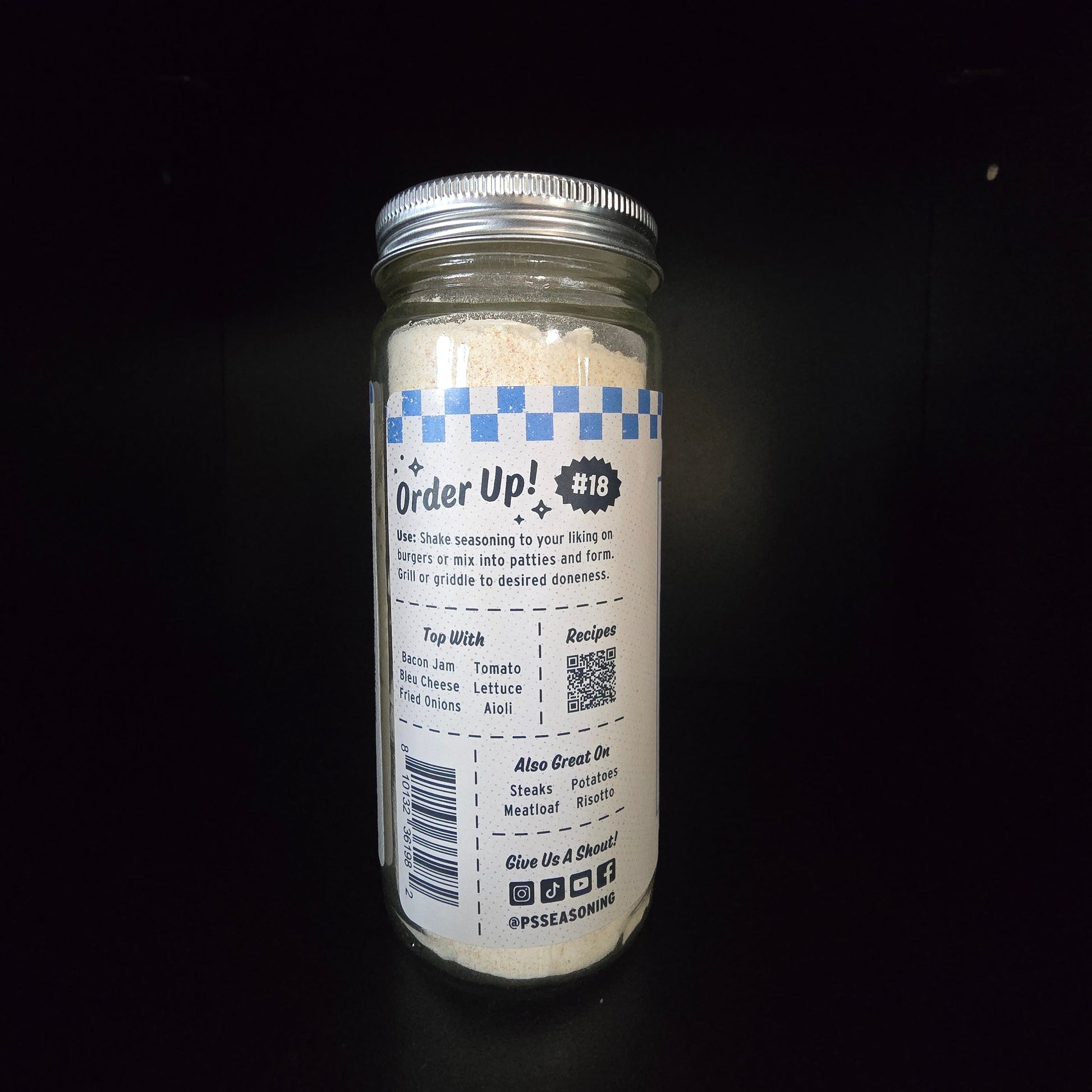 A clear glass jar sealed with a silver metal lid, and standing upright against a black background. The label reads 'Order Up!' with a blue-and-white check pattern and small text below.