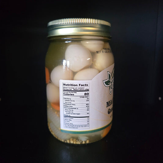 A glass jar filled with garlic onions in oil, sealed with a gold metal lid, and featuring a white label with nutrition facts, set against a dark background.