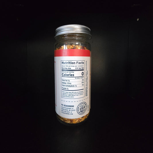 A clear spice jar with a silver metal lid, showing a white nutrition facts label and red top band, set against a solid black background.
