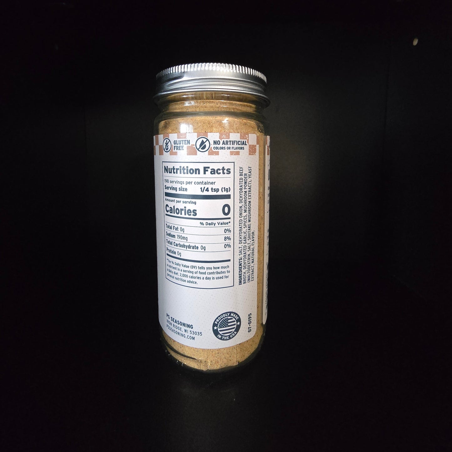 A clear glass jar filled with a light brown powder, sealed with a silver metal lid, and featuring a white nutrition facts label, set against a solid black background.