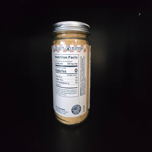 A clear glass jar filled with a light brown powder, sealed with a silver metal lid, and featuring a white nutrition facts label, set against a solid black background.