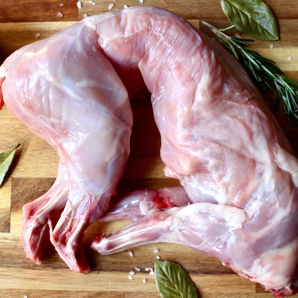 whole rabbit on a cutting board background with herbs surrounding